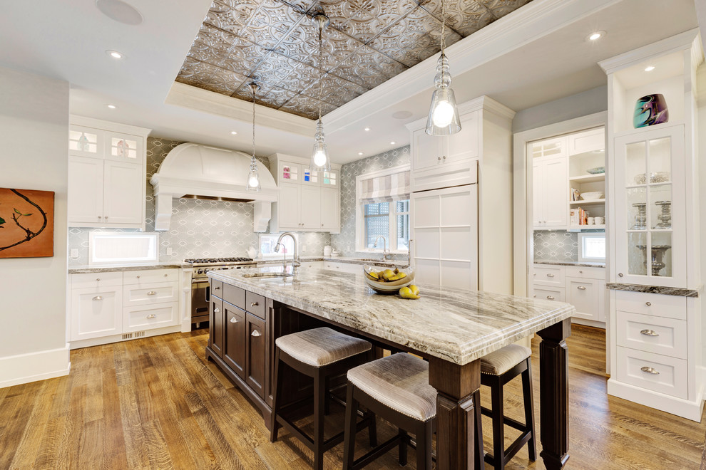 Elegant u-shaped light wood floor eat-in kitchen photo in Calgary with an undermount sink, recessed-panel cabinets, white cabinets, an island, gray backsplash and white appliances