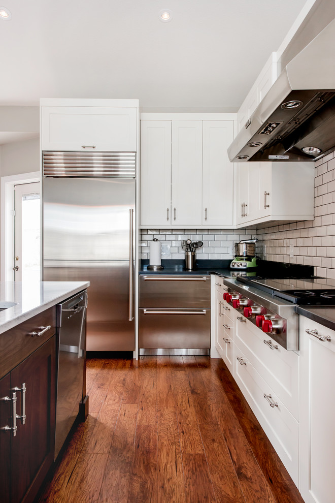 Inspiration for a large transitional u-shaped medium tone wood floor kitchen pantry remodel in Calgary with a single-bowl sink, shaker cabinets, white cabinets, quartz countertops, white backsplash, subway tile backsplash, stainless steel appliances and an island