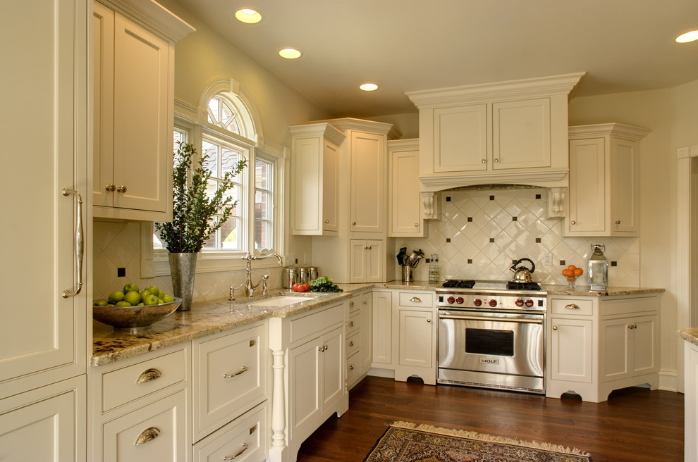 Immagine di una cucina a L tradizionale con top in granito, lavello sottopiano, ante a filo, ante bianche, paraspruzzi bianco e elettrodomestici in acciaio inossidabile
