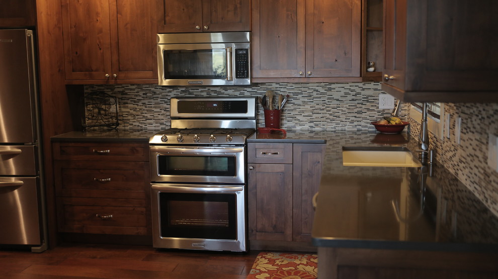 Foto på ett avskilt, mellanstort vintage l-kök, med en undermonterad diskho, släta luckor, skåp i mellenmörkt trä, bänkskiva i kvarts, flerfärgad stänkskydd, stänkskydd i glaskakel, rostfria vitvaror och mellanmörkt trägolv
