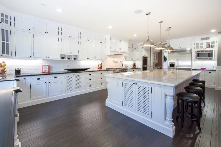 Example of a large classic l-shaped dark wood floor and brown floor eat-in kitchen design in Los Angeles with an undermount sink, shaker cabinets, white cabinets, quartzite countertops, white backsplash, porcelain backsplash, stainless steel appliances, an island and black countertops