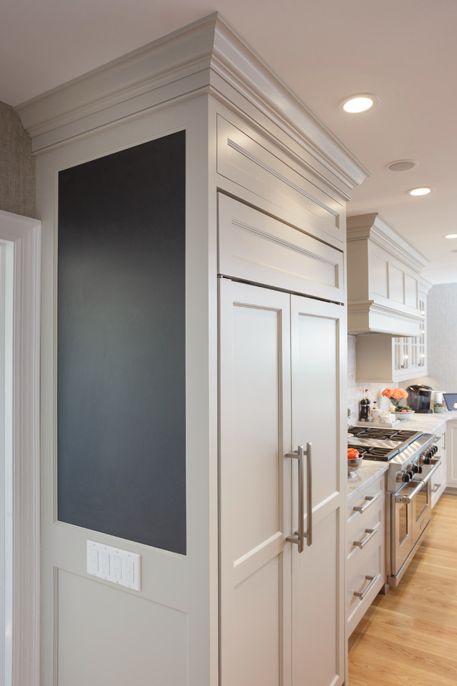 Enclosed kitchen - large traditional u-shaped light wood floor and beige floor enclosed kitchen idea in Philadelphia with an undermount sink, recessed-panel cabinets, white cabinets, marble countertops, white backsplash, marble backsplash, paneled appliances and two islands