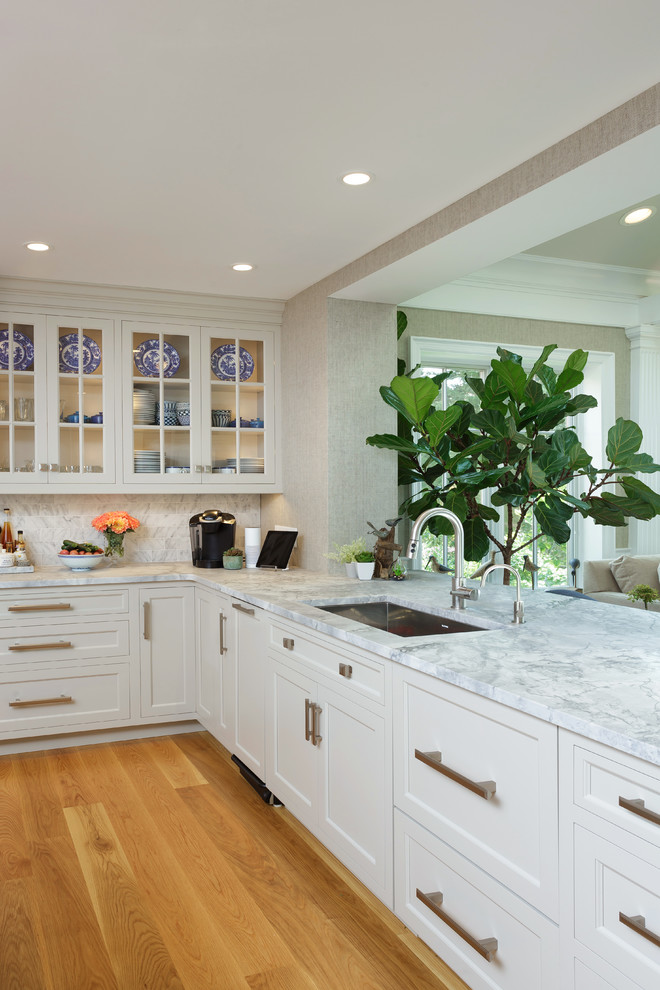 Inspiration for a large timeless u-shaped light wood floor and beige floor enclosed kitchen remodel in Philadelphia with an undermount sink, recessed-panel cabinets, white cabinets, marble countertops, white backsplash, marble backsplash, paneled appliances and two islands