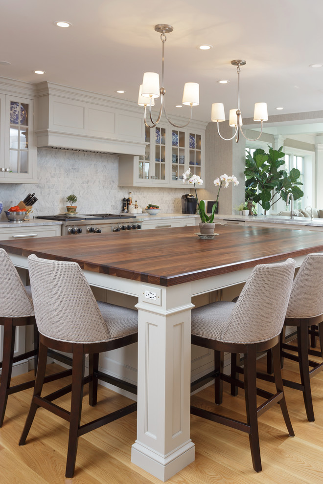 Example of a large classic u-shaped light wood floor and beige floor enclosed kitchen design in Philadelphia with an undermount sink, recessed-panel cabinets, white cabinets, marble countertops, white backsplash, marble backsplash, paneled appliances and two islands