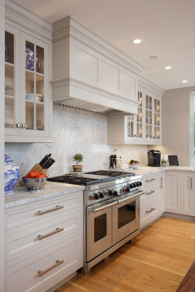 Large elegant u-shaped light wood floor and beige floor enclosed kitchen photo in Philadelphia with an undermount sink, recessed-panel cabinets, white cabinets, marble countertops, white backsplash, marble backsplash, paneled appliances and two islands