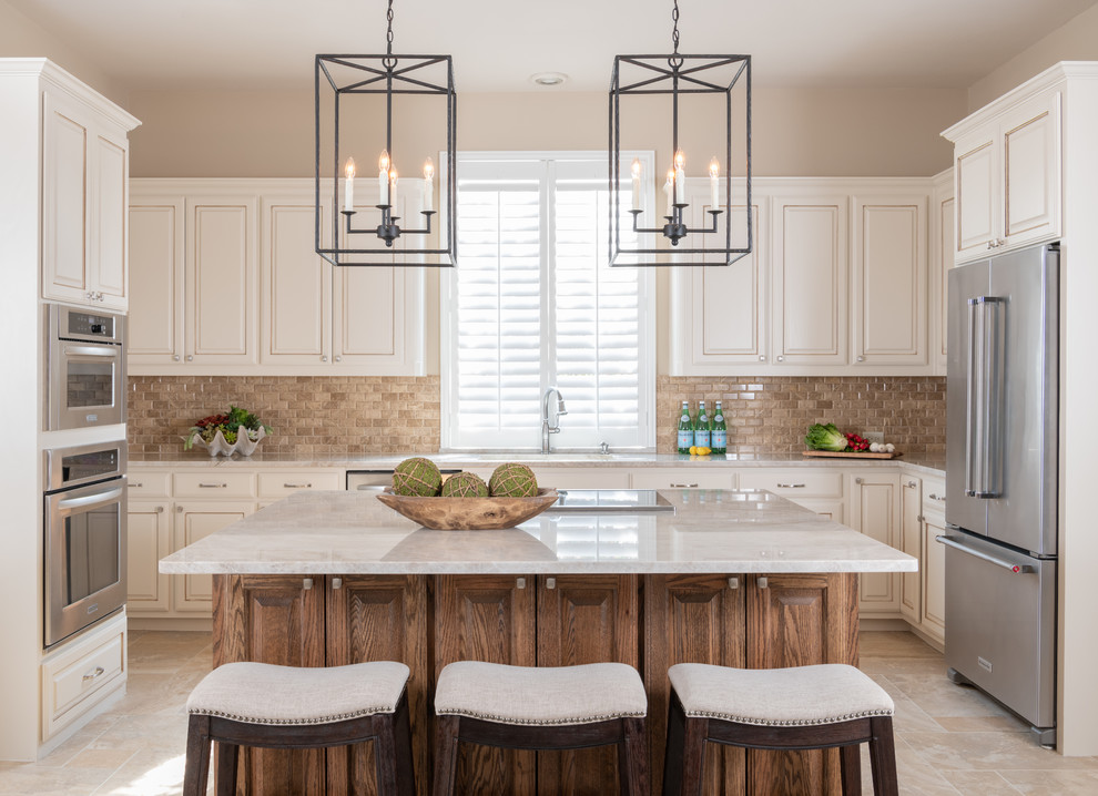 Inspiration for a mid-sized timeless u-shaped travertine floor and beige floor kitchen remodel in Dallas with raised-panel cabinets, beige cabinets, quartzite countertops, beige backsplash, marble backsplash, stainless steel appliances, an island and beige countertops
