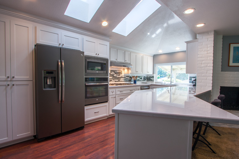 Mid-sized transitional u-shaped dark wood floor eat-in kitchen photo in Sacramento with an undermount sink, shaker cabinets, white cabinets, quartz countertops, multicolored backsplash, glass tile backsplash, colored appliances and a peninsula