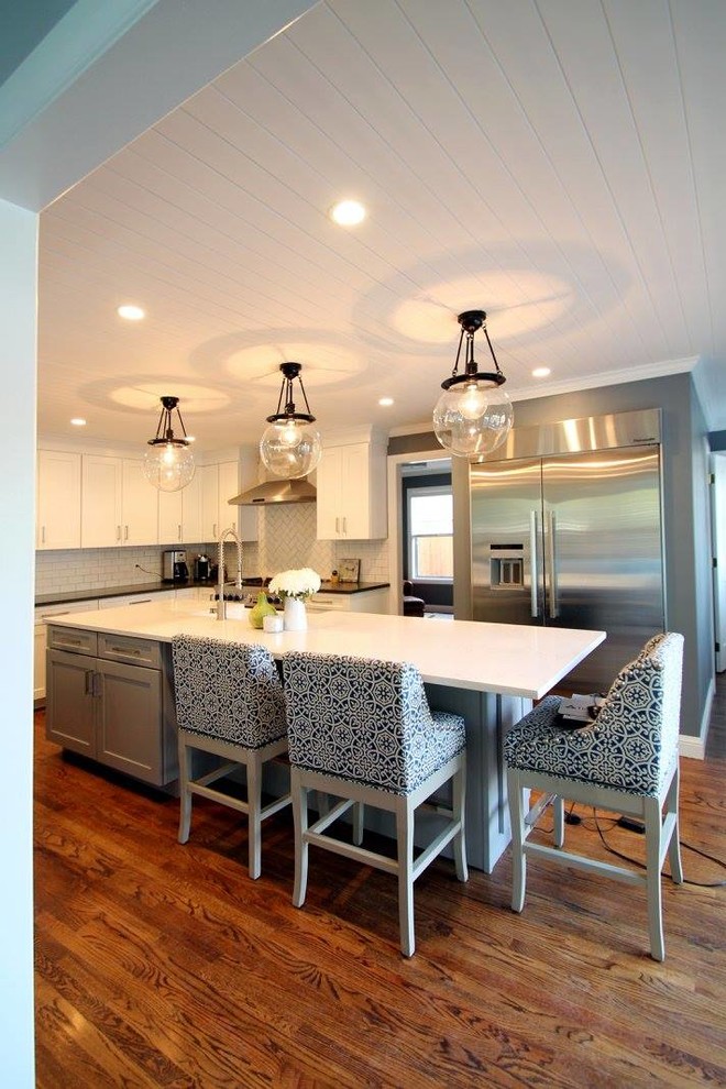 Eat-in kitchen - large transitional u-shaped dark wood floor eat-in kitchen idea in Denver with a farmhouse sink, shaker cabinets, gray cabinets, quartzite countertops, white backsplash, ceramic backsplash, stainless steel appliances and an island