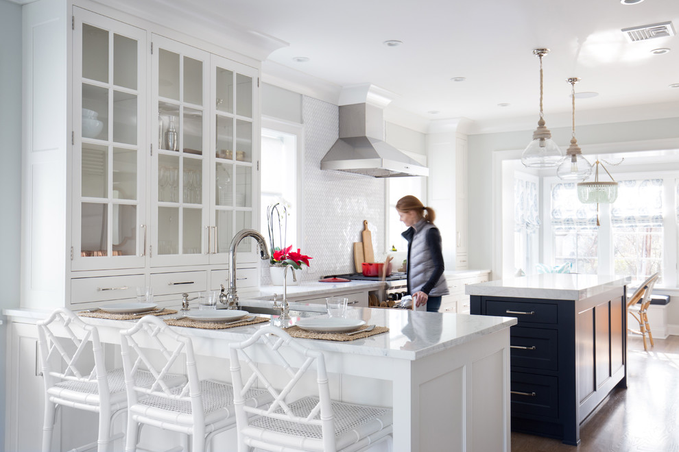 Mid-sized transitional l-shaped medium tone wood floor eat-in kitchen photo in New York with an undermount sink, shaker cabinets, white cabinets, marble countertops, white backsplash, stone tile backsplash, stainless steel appliances and an island