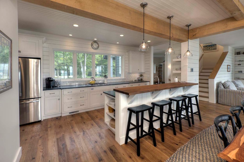 Mid-sized beach style galley dark wood floor open concept kitchen photo in Other with beaded inset cabinets, white cabinets, white backsplash, stainless steel appliances, a peninsula and subway tile backsplash