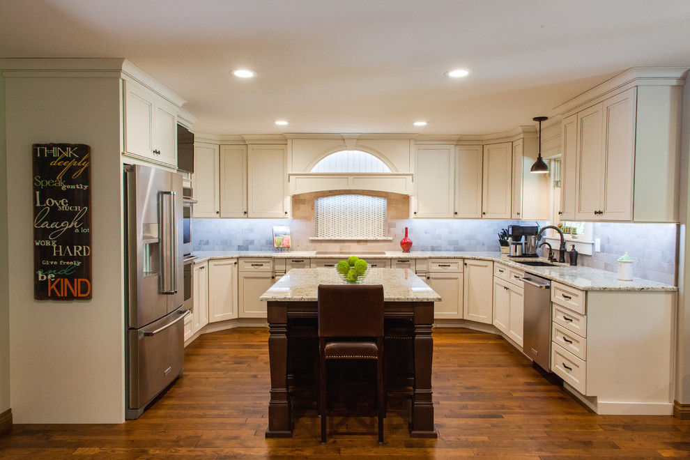 Inredning av ett klassiskt stort kök och matrum, med en enkel diskho, luckor med infälld panel, vita skåp, granitbänkskiva, flerfärgad stänkskydd, rostfria vitvaror, mellanmörkt trägolv och en köksö