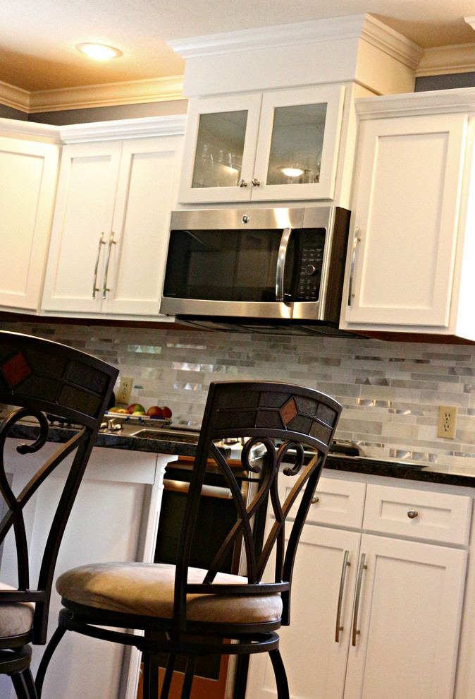 Foto på ett stort vintage kök, med en undermonterad diskho, skåp i shakerstil, vita skåp, granitbänkskiva, grått stänkskydd, stänkskydd i stickkakel, rostfria vitvaror, mellanmörkt trägolv och en köksö