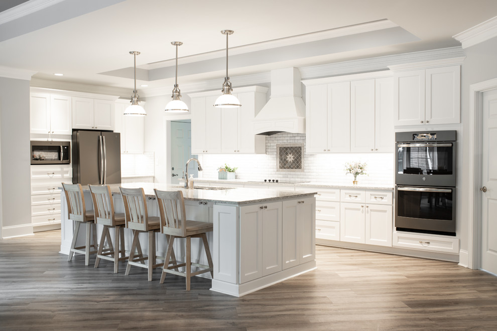 Example of a huge transitional l-shaped light wood floor and gray floor eat-in kitchen design in Charlotte with a triple-bowl sink, shaker cabinets, white cabinets, quartz countertops, white backsplash, marble backsplash, stainless steel appliances, an island and multicolored countertops