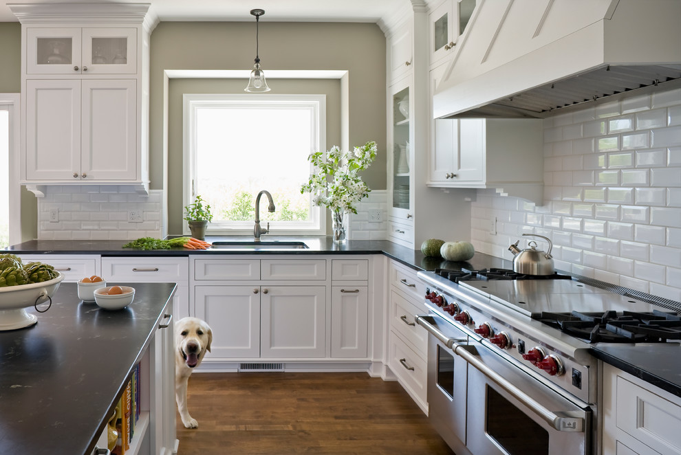 Inredning av ett klassiskt mellanstort kök, med en undermonterad diskho, luckor med infälld panel, vita skåp, granitbänkskiva, vitt stänkskydd, stänkskydd i keramik, rostfria vitvaror, mellanmörkt trägolv och en köksö