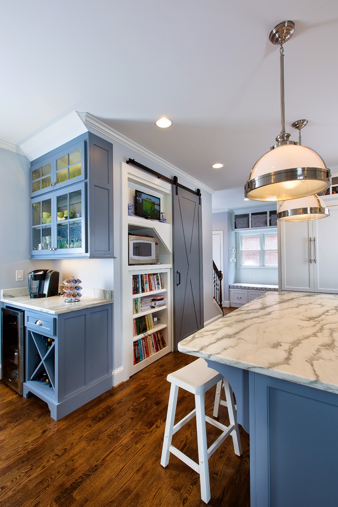 Inspiration for a large transitional l-shaped medium tone wood floor eat-in kitchen remodel in Atlanta with a farmhouse sink, shaker cabinets, white cabinets, soapstone countertops, white backsplash, stone tile backsplash, stainless steel appliances and an island