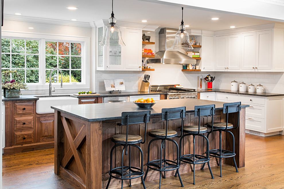 Large country u-shaped medium tone wood floor eat-in kitchen photo in New York with a farmhouse sink, shaker cabinets, white cabinets, granite countertops, white backsplash, ceramic backsplash, stainless steel appliances and an island