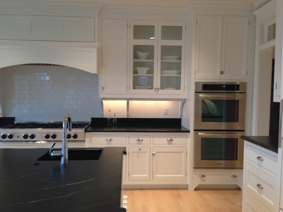 Large traditional u-shaped kitchen/diner in Portland Maine with a submerged sink, beaded cabinets, white cabinets, soapstone worktops, white splashback, metro tiled splashback, stainless steel appliances, light hardwood flooring and an island.