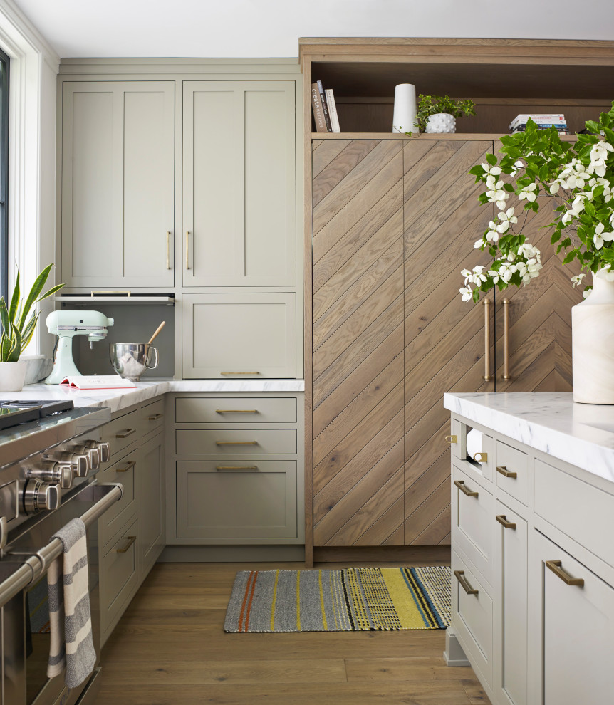 Cette photo montre une grande cuisine ouverte chic en L et bois clair avec un évier encastré, un placard à porte shaker, plan de travail en marbre, une crédence blanche, une crédence en marbre, un électroménager en acier inoxydable, parquet clair, îlot, un sol beige et un plan de travail blanc.