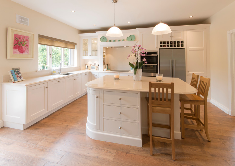 Example of a mid-sized classic l-shaped light wood floor eat-in kitchen design in Dublin with a drop-in sink, shaker cabinets, quartzite countertops, stone slab backsplash and an island