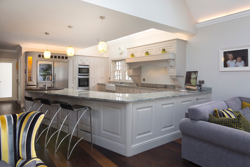 Inspiration for a large traditional u-shaped kitchen/diner in Dublin with a belfast sink, raised-panel cabinets, granite worktops and a breakfast bar.
