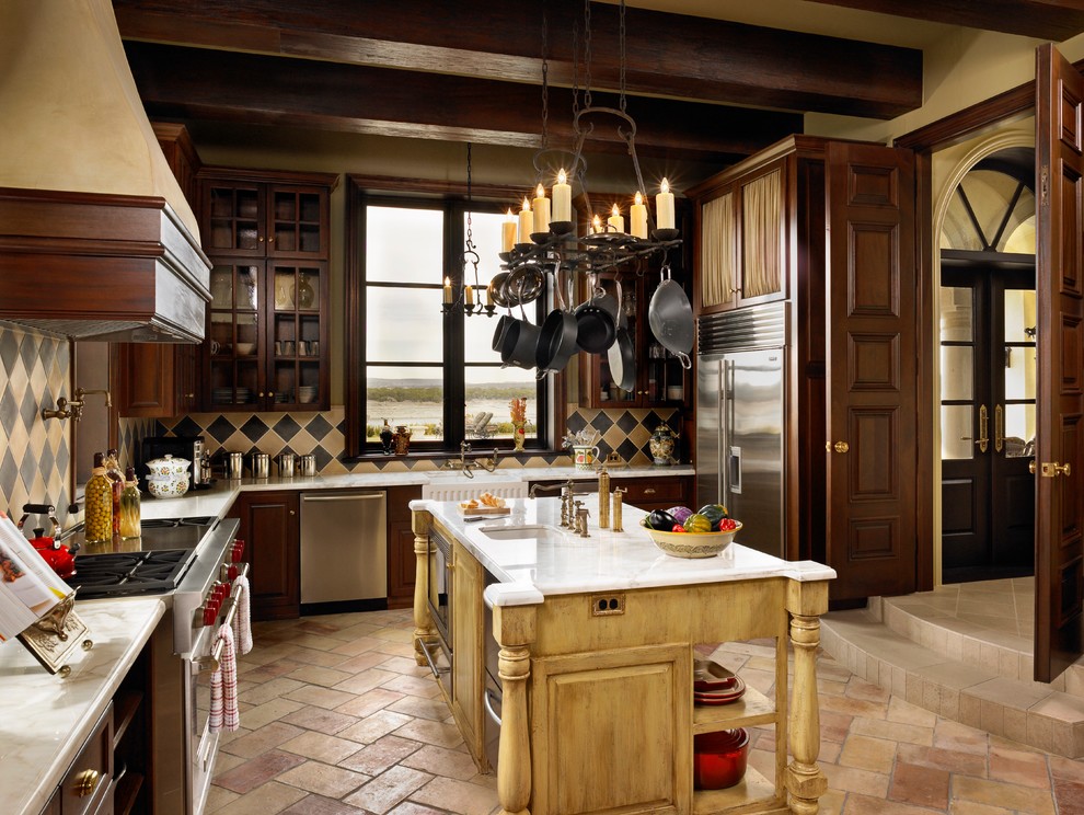 На фото: отдельная кухня в средиземноморском стиле с с полувстраиваемой мойкой (с передним бортиком), стеклянными фасадами, темными деревянными фасадами, разноцветным фартуком и техникой из нержавеющей стали с