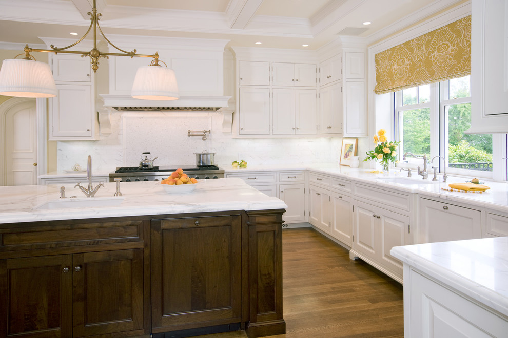 Design ideas for a large traditional u-shaped kitchen/diner in San Francisco with a belfast sink, beaded cabinets, white cabinets, marble worktops, white splashback, stainless steel appliances, medium hardwood flooring, an island, marble splashback and brown floors.