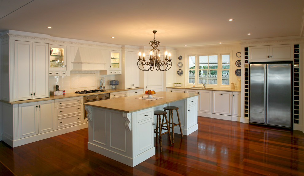 Inspiration for a large timeless l-shaped light wood floor kitchen pantry remodel in Brisbane with recessed-panel cabinets, yellow cabinets, granite countertops, white backsplash, ceramic backsplash and an island