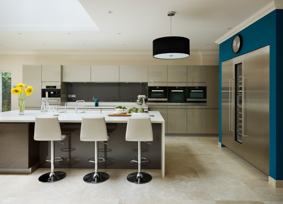 Modern inredning av ett kök, med en dubbel diskho, släta luckor, grått stänkskydd, glaspanel som stänkskydd, rostfria vitvaror och en köksö