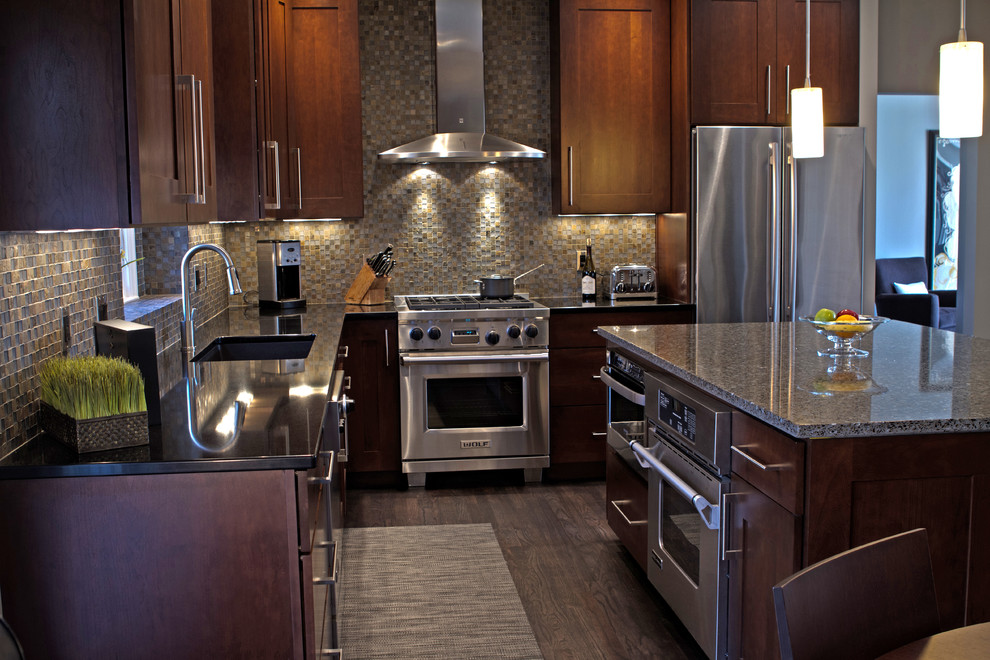 Foto på ett funkis l-kök, med bänkskiva i kvarts, rostfria vitvaror, skåp i shakerstil, skåp i mörkt trä och stänkskydd i stenkakel