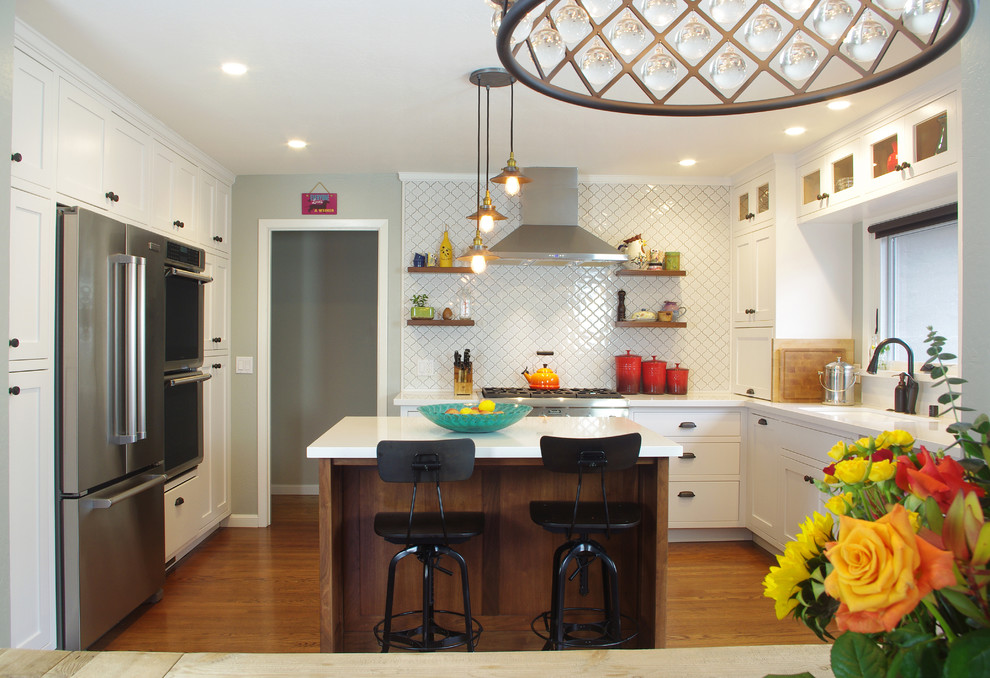 Traditional kitchen in San Francisco with white cabinets, white splashback, medium hardwood flooring and an island.