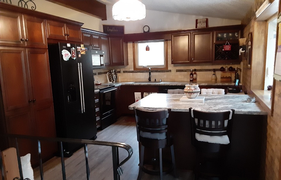 他の地域にある中くらいなトラディショナルスタイルのおしゃれなキッチン (中間色木目調キャビネット、ラミネートカウンター、トラバーチンのキッチンパネル) の写真