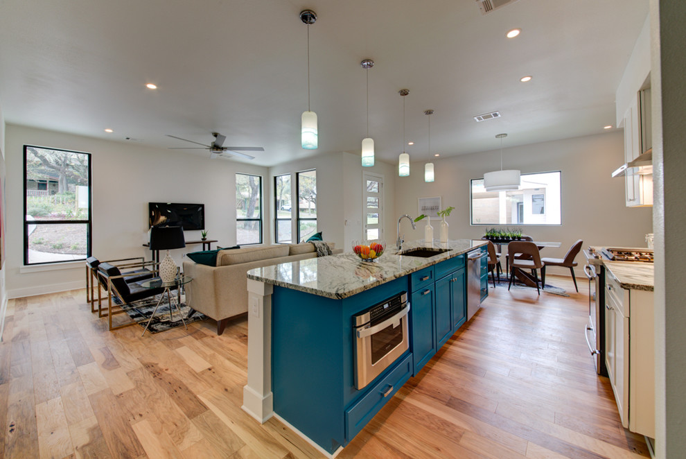 Example of a mid-sized trendy single-wall light wood floor and brown floor open concept kitchen design in Austin with shaker cabinets, granite countertops, an island, a single-bowl sink, white backsplash, subway tile backsplash, stainless steel appliances and turquoise cabinets