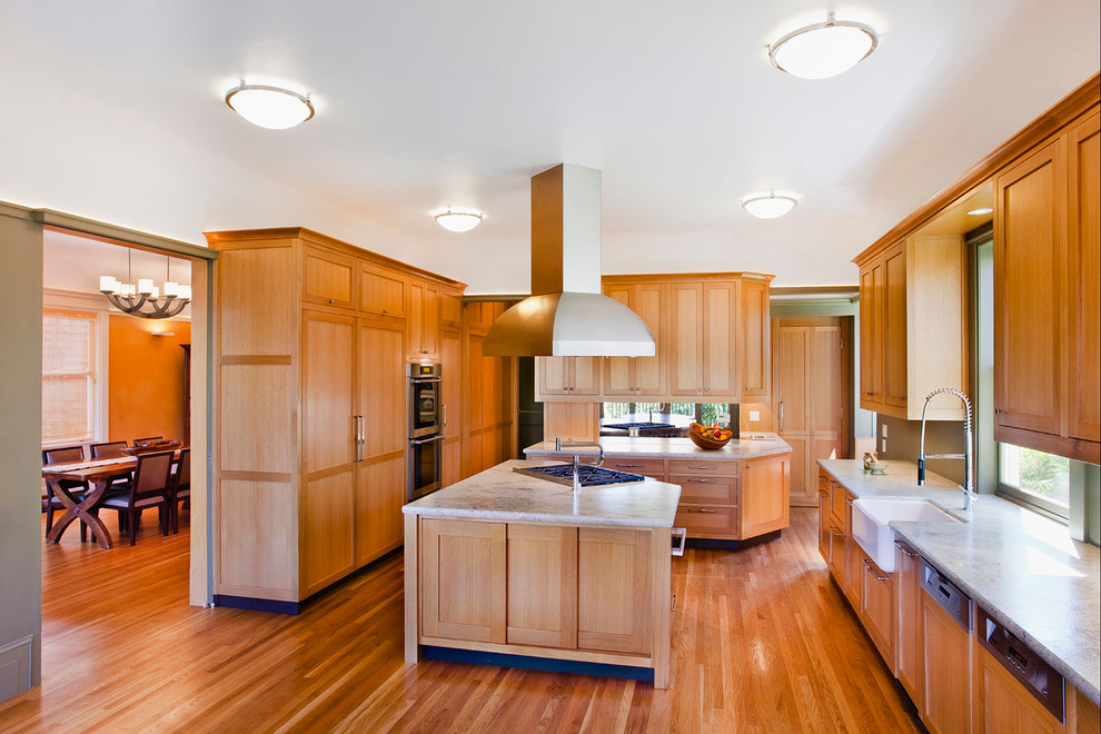 Idées déco pour une cuisine américaine parallèle classique en bois brun avec un évier de ferme, un placard avec porte à panneau encastré, un plan de travail en granite, un sol en bois brun et îlot.
