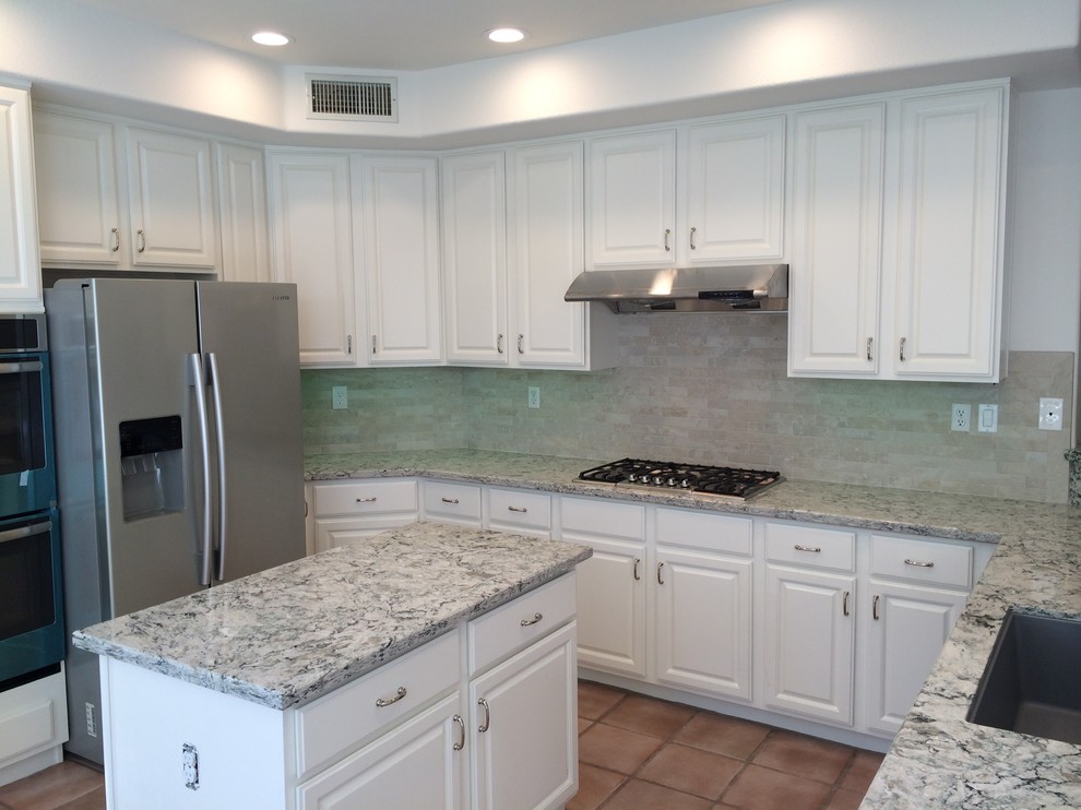 This is an example of a medium sized traditional u-shaped kitchen in San Diego with a submerged sink, raised-panel cabinets, white cabinets, granite worktops, beige splashback, stone tiled splashback, stainless steel appliances, terracotta flooring and an island.