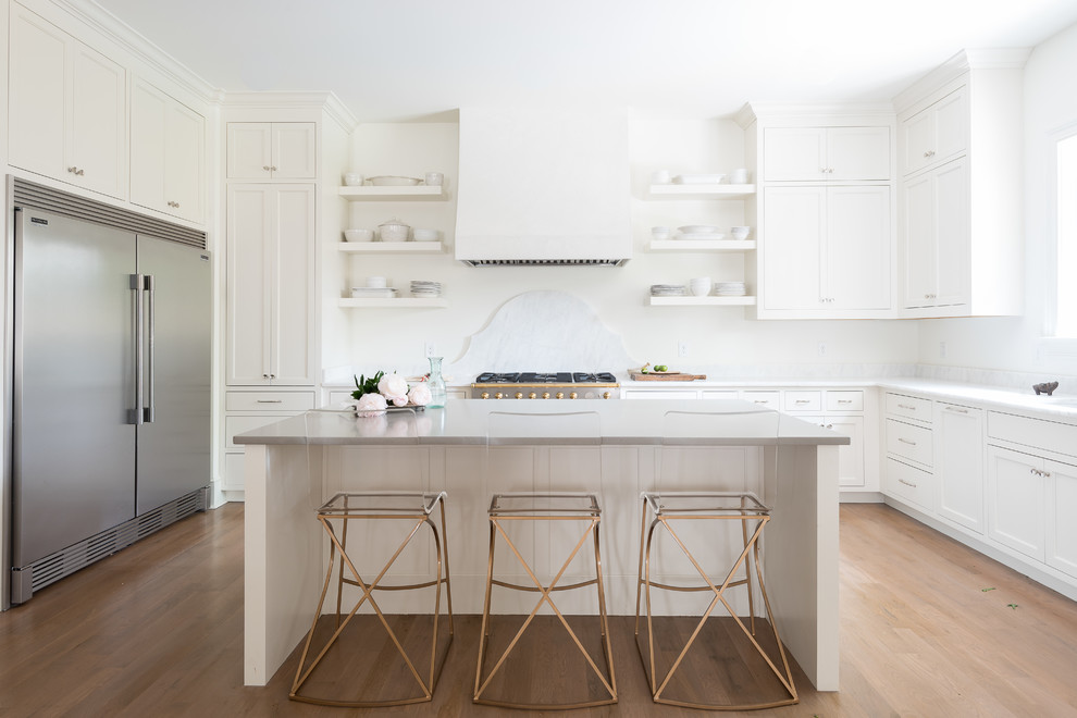 ナッシュビルにあるトランジショナルスタイルのおしゃれなアイランドキッチン (シェーカースタイル扉のキャビネット、白いキャビネット、白いキッチンパネル、シルバーの調理設備、淡色無垢フローリング、ベージュの床) の写真