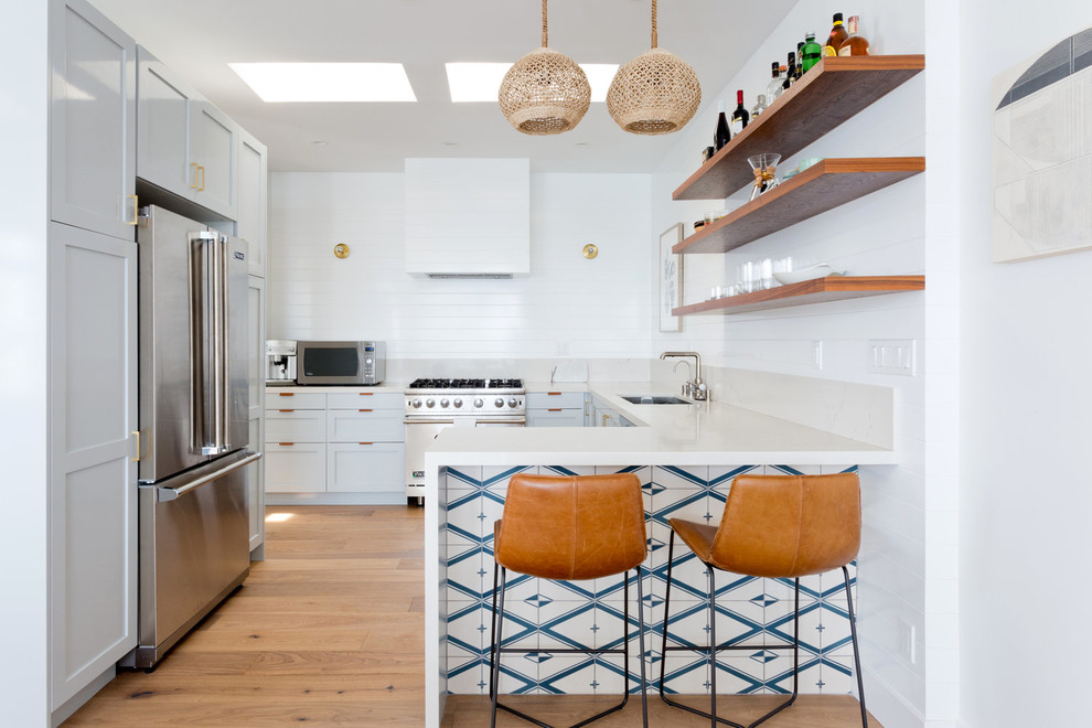 Photo of a traditional u-shaped kitchen in San Francisco with a submerged sink, shaker cabinets, grey cabinets, stainless steel appliances, medium hardwood flooring, a breakfast bar and brown floors.