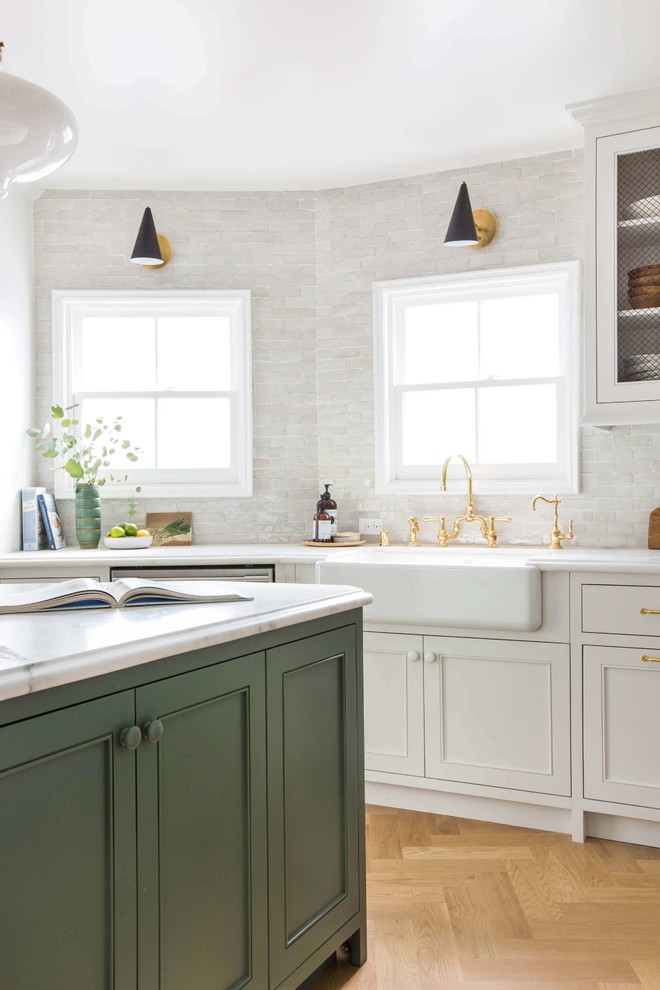 This is an example of a small traditional u-shaped kitchen/diner in San Francisco with shaker cabinets, white cabinets, marble worktops, white splashback, terracotta splashback, stainless steel appliances, light hardwood flooring and an island.