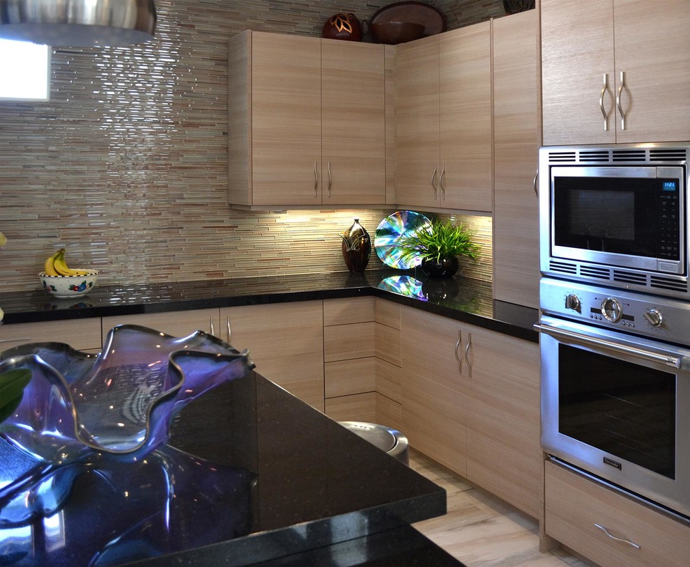 Modern inredning av ett avskilt l-kök, med släta luckor, skåp i mellenmörkt trä, granitbänkskiva, flerfärgad stänkskydd, stänkskydd i stickkakel, rostfria vitvaror, vinylgolv och en köksö