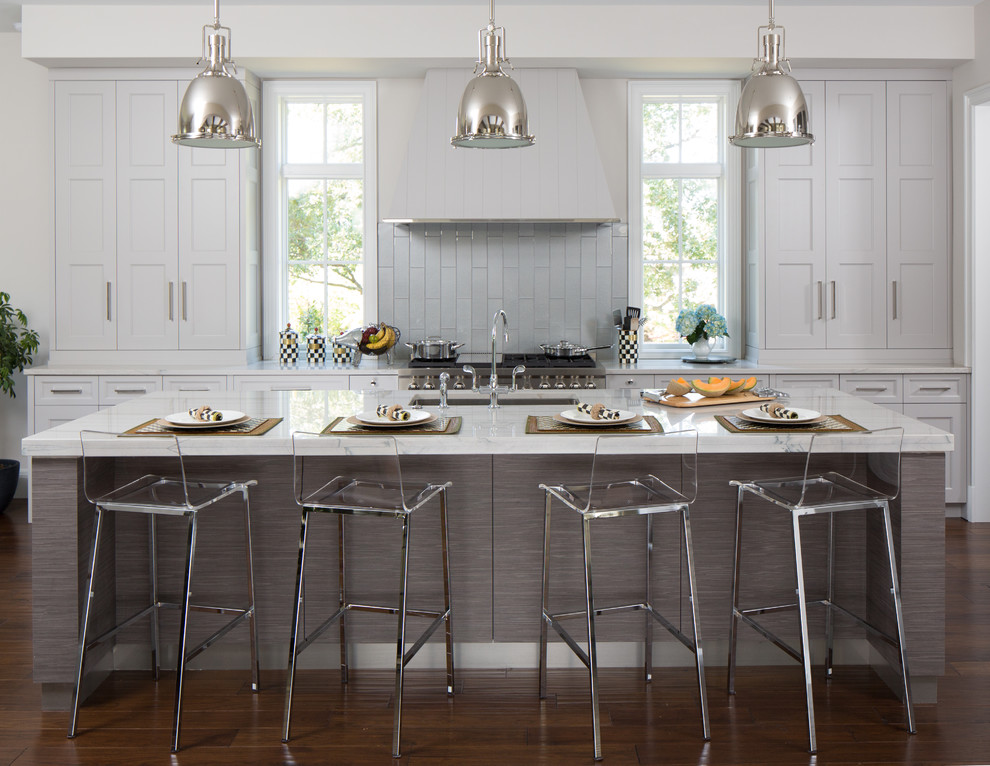 Klassisk inredning av ett mellanstort kök, med en undermonterad diskho, luckor med infälld panel, grå skåp, granitbänkskiva, grått stänkskydd, stänkskydd i glaskakel, integrerade vitvaror, mörkt trägolv och en köksö