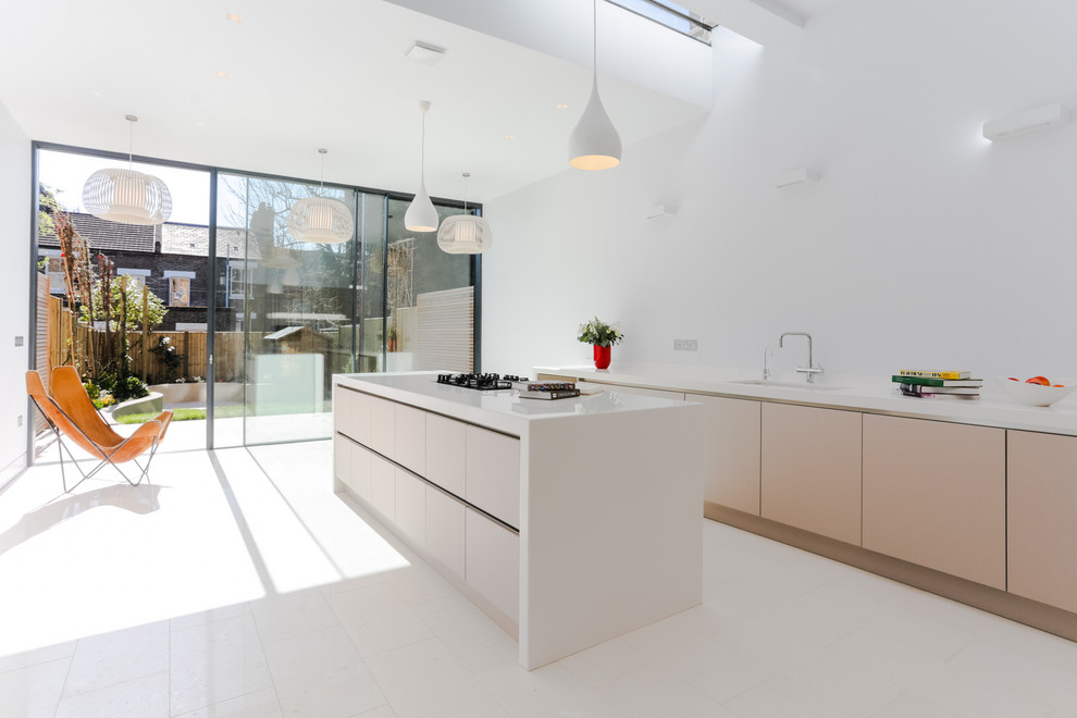 Mid-sized trendy l-shaped ceramic tile and white floor open concept kitchen photo in London with an integrated sink, flat-panel cabinets, white cabinets, solid surface countertops, an island and white countertops
