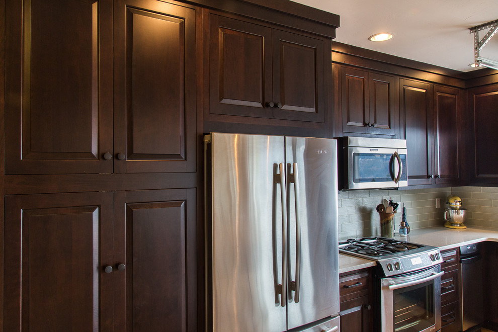 Exempel på ett mellanstort modernt kök, med en undermonterad diskho, luckor med upphöjd panel, skåp i mörkt trä, bänkskiva i kvarts, grönt stänkskydd, stänkskydd i glaskakel, rostfria vitvaror, linoleumgolv och en köksö