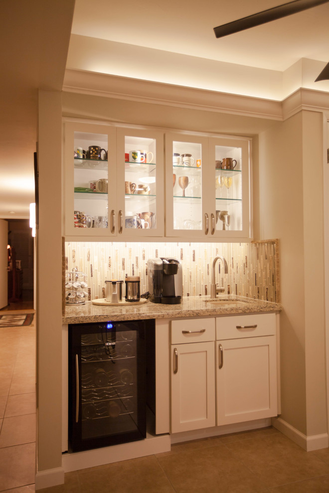 This is an example of a large contemporary l-shaped home bar in Phoenix with a submerged sink, shaker cabinets, white cabinets, granite worktops, multi-coloured splashback, glass tiled splashback and ceramic flooring.