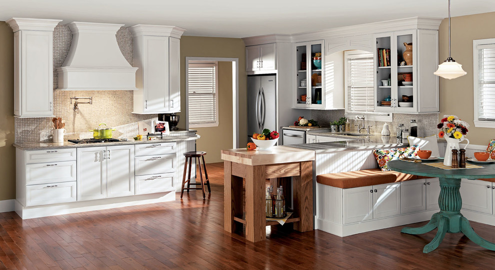 Klassisk inredning av ett kök, med luckor med infälld panel, vita skåp, granitbänkskiva, beige stänkskydd, rostfria vitvaror och en halv köksö