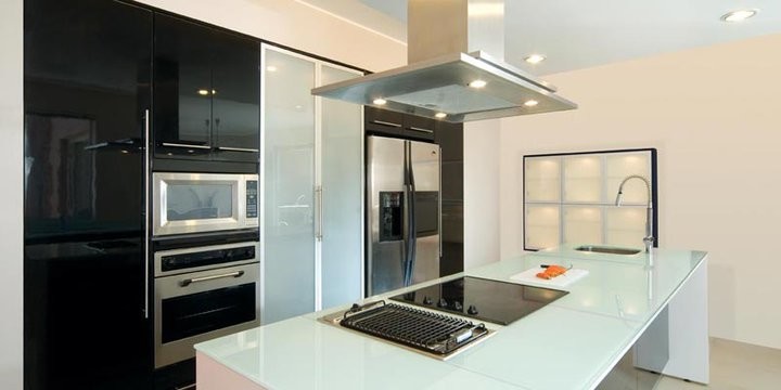 Идея дизайна: параллельная кухня-гостиная среднего размера в стиле модернизм с врезной мойкой, плоскими фасадами, черными фасадами, стеклянной столешницей, техникой из нержавеющей стали, островом и бетонным полом