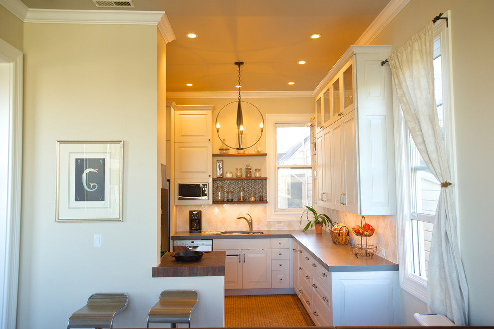 Exempel på ett mellanstort klassiskt l-kök, med en dubbel diskho, luckor med upphöjd panel, vita skåp, bänkskiva i koppar, beige stänkskydd, stänkskydd i keramik, rostfria vitvaror, korkgolv och beiget golv