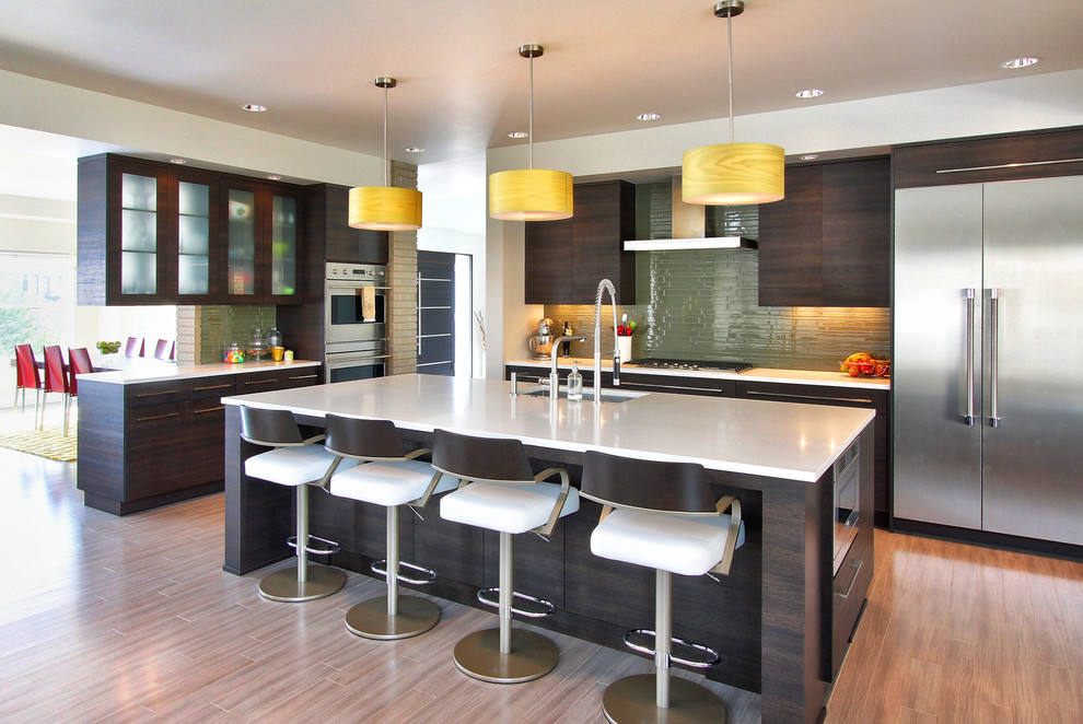 Offene Moderne Küche in L-Form mit flächenbündigen Schrankfronten, dunklen Holzschränken, Küchenrückwand in Grün, Küchengeräten aus Edelstahl, braunem Holzboden und Kücheninsel in Boise