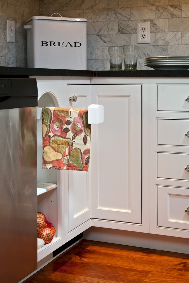 Inredning av ett klassiskt mellanstort kök, med en undermonterad diskho, luckor med infälld panel, vita skåp, marmorbänkskiva, vitt stänkskydd, stänkskydd i tunnelbanekakel, rostfria vitvaror, mellanmörkt trägolv och en köksö