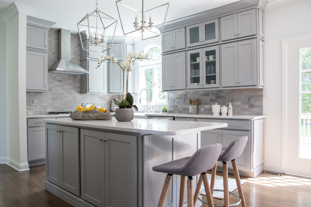 Klassische Küche in grau-weiß in L-Form mit Schrankfronten im Shaker-Stil, grauen Schränken, Küchenrückwand in Grau, dunklem Holzboden, Kücheninsel und braunem Boden in Philadelphia