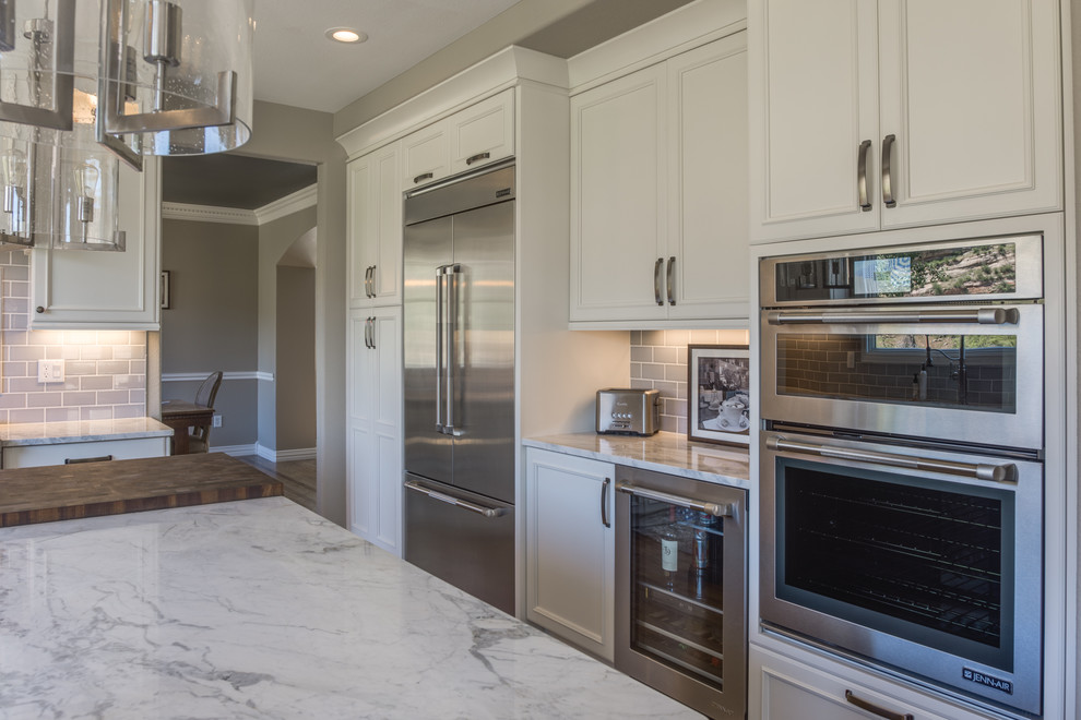 Large transitional l-shaped medium tone wood floor and brown floor open concept kitchen photo in Denver with a farmhouse sink, flat-panel cabinets, white cabinets, quartzite countertops, blue backsplash, ceramic backsplash, stainless steel appliances and an island