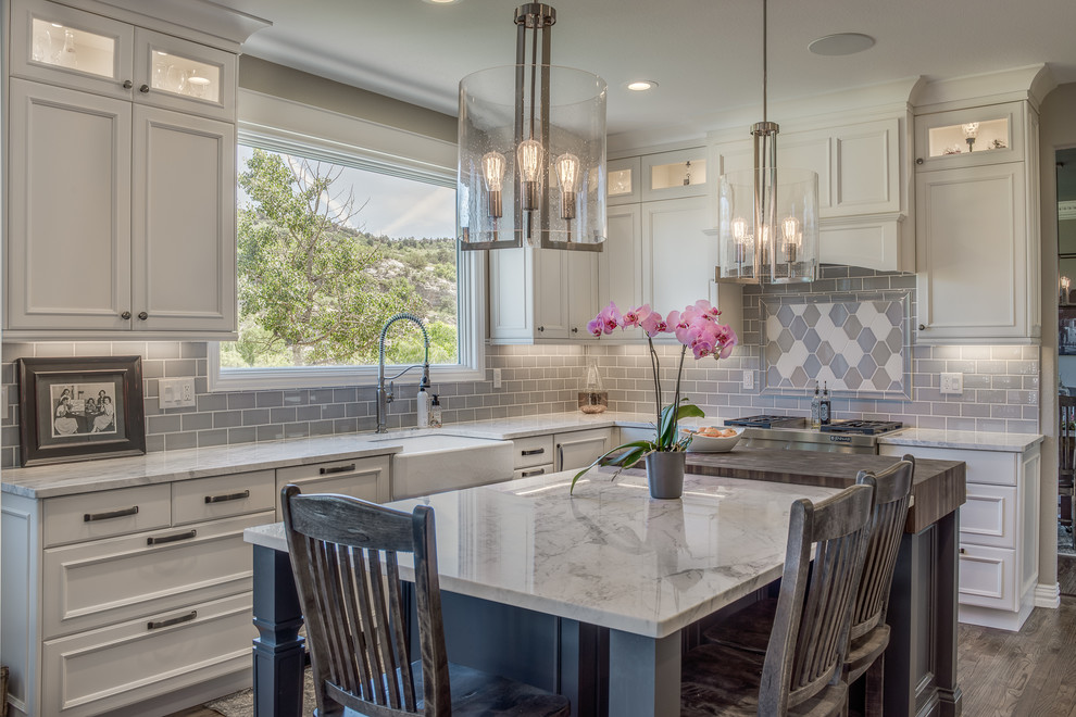Inspiration for a large transitional l-shaped medium tone wood floor and brown floor open concept kitchen remodel in Denver with a farmhouse sink, flat-panel cabinets, white cabinets, quartzite countertops, blue backsplash, ceramic backsplash, stainless steel appliances and an island